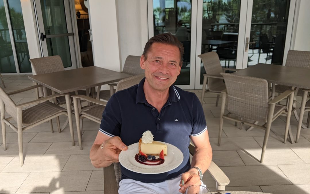 The picture is describing a men with a birthday cake celebrating his birthday in the private bay colony beach club naples florida