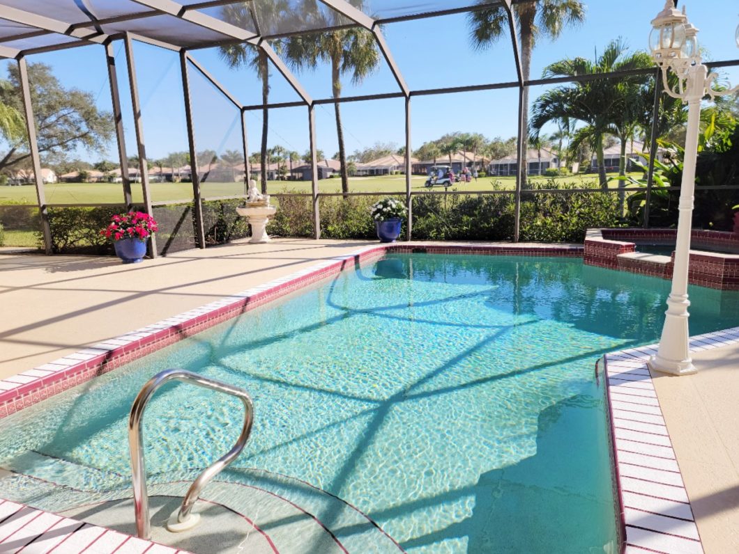 The picture shows a screened lanai with pool and view to the golf course