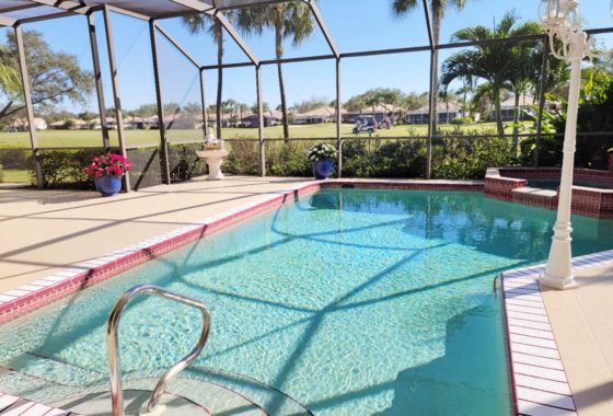 The picture shows a screened lanai with pool and view to the golf course