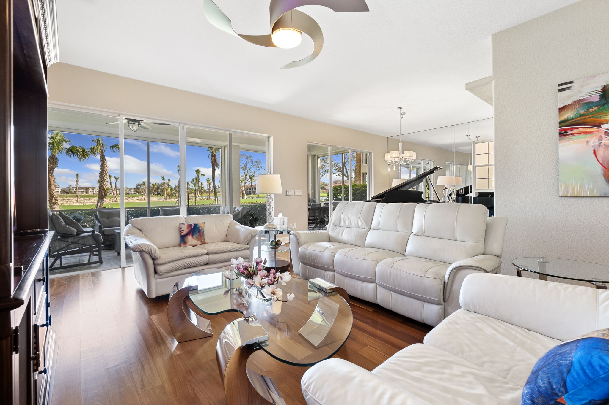 A spacious living room featuring a large window that allows natural light and a prominent ceiling fan for airflow.