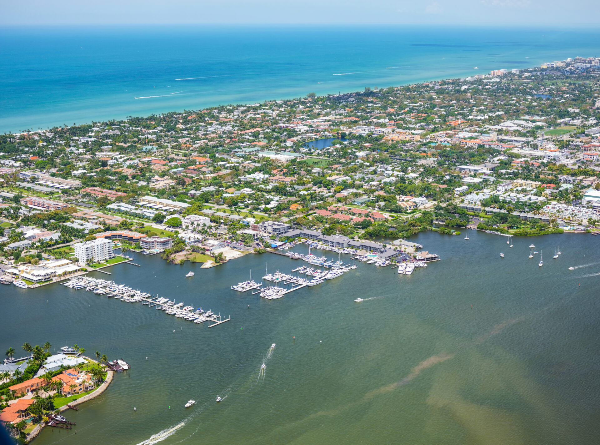Scenic view of Old Naples with the Cove Inn hotel overlooking Naples Bay, leading out toward the Gulf of Mexico under a clear Florida sky.