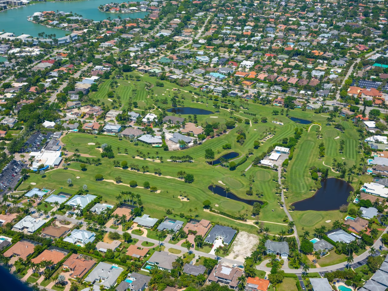 Aerial view of The Moorings in Naples, Florida, featuring residential homes, golf course fairways, and waterfront access.